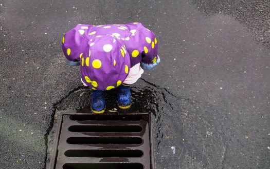 Photo of a child looking into a drain